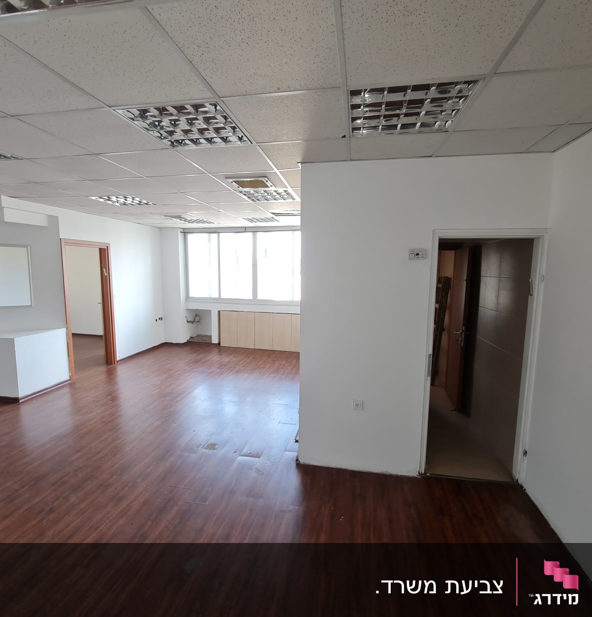 חדר עם קירות לבנים ורצפת עץ כהה